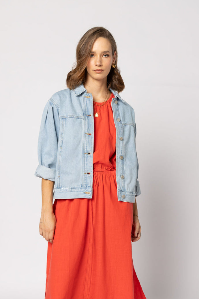 Woman wearing a red dress with a light blue denim jacket on a white background