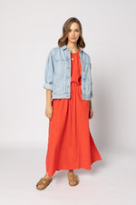 Woman wearing a red dress with a light blue denim jacket on a white background
